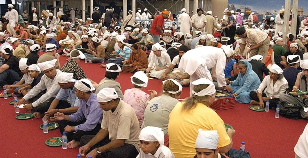 Devotees and visitors sharing a communal meal at the langar hall of the Golden Temple, emphasizing equality and service.