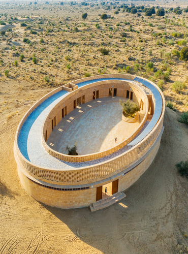 Arial view of the Rajkumari Ratnavati Girls' School in Jaisalmer, Rajasthan, showcasing its oval architectural design in the desert landscape.